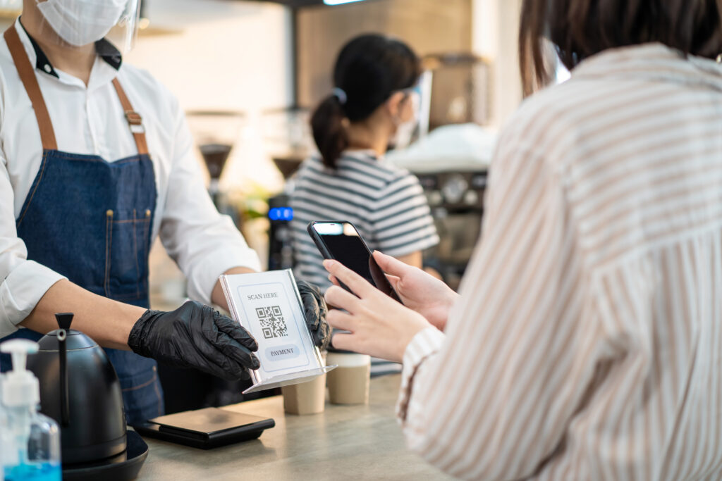 A customer at a cafe pays via QR payment. Soundboxes free staff from manually checking each payment.