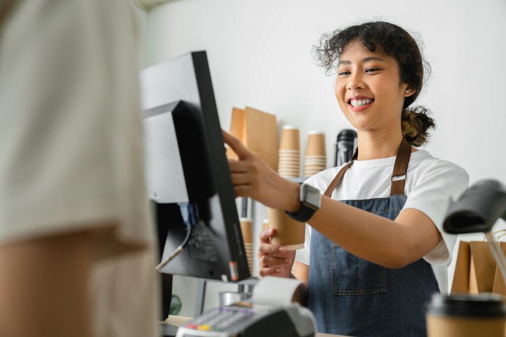 A barista handles a transaction using a POS system during the lunch rush.